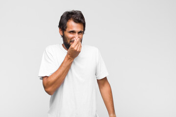 young latin handsome man covering face with hand and putting other hand up front to stop camera,...