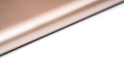 Rose gold colored metal smartphone case, closeup macro detail forming diagonal line with space for text right, abstract technology background © Lubo Ivanko