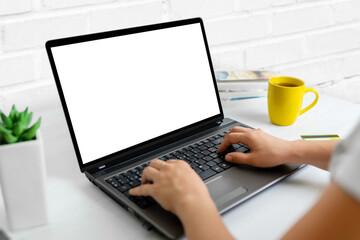 Laptop mockup close-up. Woman typing on the keyboard concept. White office desk with plant and coffee mug