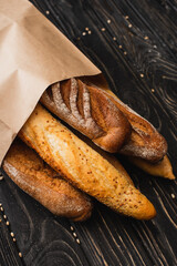 fresh baked baguette loaves in paper bag on wooden surface
