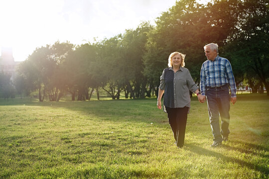 Happy senior couple walking in the park at sunset