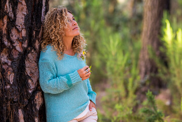 Portrait of beautiful adult caucasian woman enjoying the feeling with the nature - people and wood forest leisure activity - alternative recreation active female with trendy blue sweater