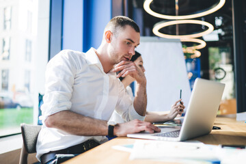 Focused coworkers surfing laptop in conference room