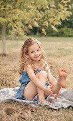 Lifestyle summer portrait of little girl sitting in the park