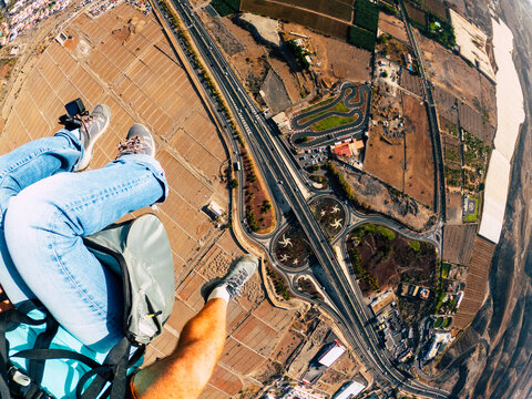 Air view of people couple doing paraglyde adrenaline experience - pilot and passenger paraglyiding over the city - outdoor excursion leisure activity