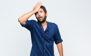 young latin handsome man raising palm to forehead thinking oops, after making a stupid mistake or...