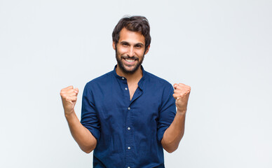 young latin handsome man feeling happy, positive and successful, celebrating victory, achievements...
