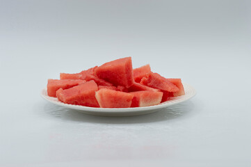 WATERMELON CUT INTO PIECES ON A WHITE PLATE