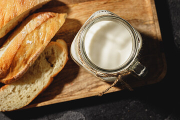 Glass of milk with bread slices on black surface