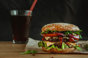 juicy powerful burger with beef and vegetables on a bun with sesame seeds.