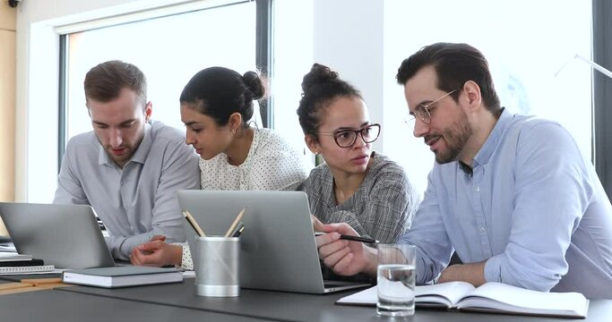 Multicultural business people group do digital marketing research use laptops at workplace. Multiethnic employees team work on computers discuss corporate project software in teamwork at office desk.
