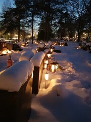 Snowy graveyard by night lit up by candles in memory of the dead in the snow outside of Helsinki in...