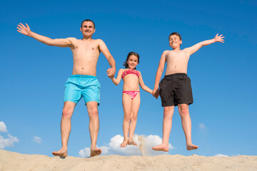 A father and children have fun playing on the sand on a sunny warm day. Happy family on vacation. Holidays, sports, lifestyle.