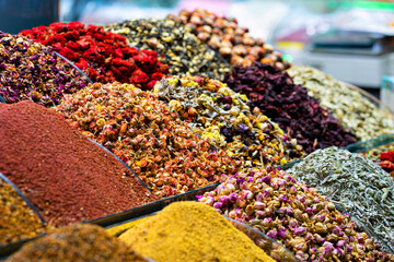 Various bright colored powder spices and fruit herbal tea and dried vegetables on market in...