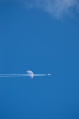 airplane crossing the moon in the sky