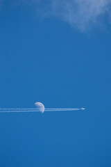 airplane crossing the moon in the sky