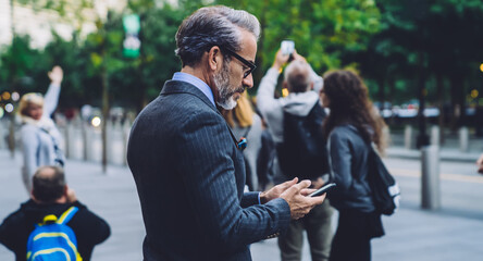 Side view of mature stylish male looking at cellphone