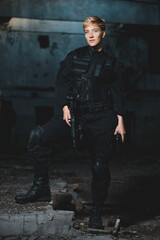 Portrait of young woman soldier in black uniform with a pistol and rifle.