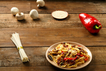 Udon with chicken and mushrooms in pad thai sauce in a beige dish near the ingredients.