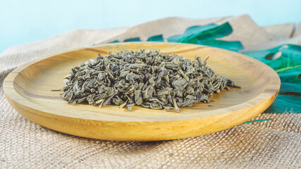 Close up shot of a wood bowl filled with dry tea leaves