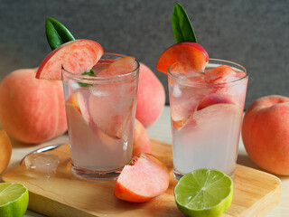Pink color peach mocktail glass on wooden cutting board for summer drink concept.