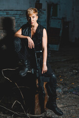Naklejka premium Portrait of young woman soldier in black uniform with a rifle posing to the camera.