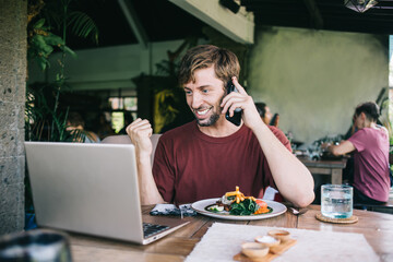 Cheerful man talking on smartphone in cafe