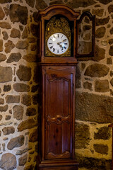 Old vintage antique bronze clock and utensil on wooden shelf, stone wall background. Antiques concept.