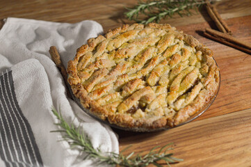 Freshly baked apple pie garnished with cinnamon and rosemary.