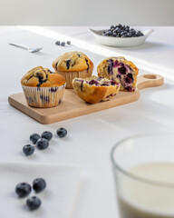 Blueberry muffins on a wooden bread board on a summer day morning .