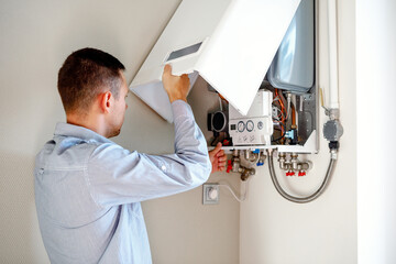 Plumber attaches Trying To Fix the Problem with the Residential Heating Equipment. Repair of a gas...