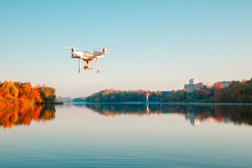 Fototapeta premium Drone copter with digital camera, blur river on autumn background