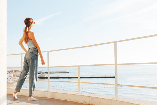  beautiful young woman standing on the balcony morning  and looking at the sea. Woman look at the sea on terrace. Back view