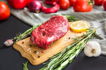 Raw beef steak on a cutting board with spices. Creative atmospheric decoration.
