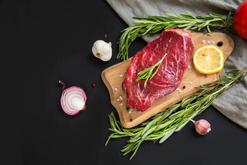Raw beef steak on a cutting board with spices. Creative atmospheric decoration.