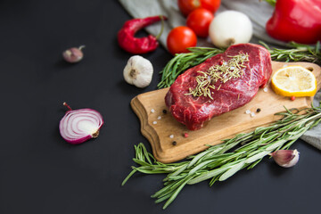 Raw beef steak on a cutting board with spices. Creative atmospheric decoration.