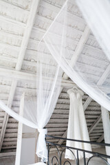 View from distance of fashionable wedding dress hanging with canopy in white room. Preparation for traditional wedding ceremony. Stylish outfit for bride. Concept of mode and bridal cloth traditions.