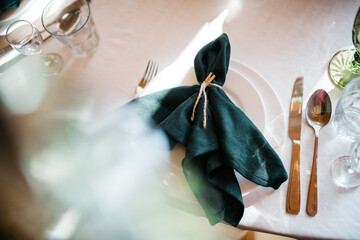 Close up of top view of valuable cutlery and glassware serving on white table, green serviette. Beautiful details of restaurant preparing for people. Tiny wedding celebration. Eating on romantic date.