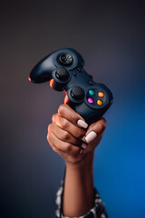 Pretty hands of afro woman grips the modern gaming joystick and lifting it up. Youth modern hobby...