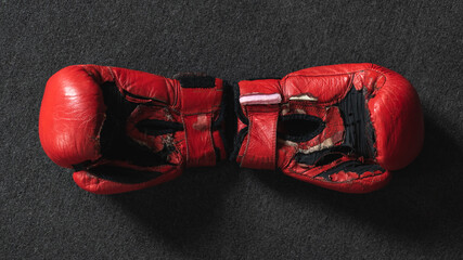 Red leather, old boxing gloves on a dark background.