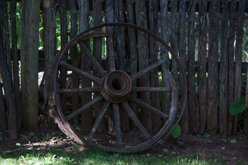 Fototapeta na wymiar Old wagon wheel leaning against a fence