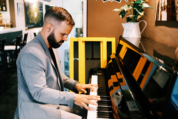 adult man wearing a grey suit playing the piano at the bar
