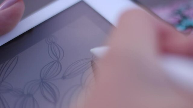 A young girl draws with a pencil on the tablet. Drawings on the tablet. Drawing with a tablet on a city street. A beautiful girl draws on the street using a tablet.