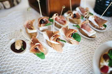 Close up of salty snacks made of baguette, olive, meat, cheese, sauce on luxury all inclusive. Tasty appetizers on wedding celebration. Delicious food on birthday pre party. Concept of simple cooking.
