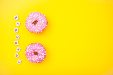pink delicious donuts on yellow background and inscription from wooden blocks happy hanukkah