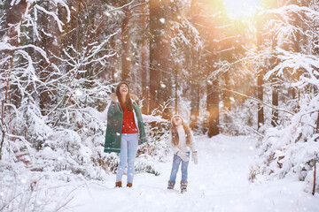 Young family for a walk. Mom and daughter are walking in a winter park.