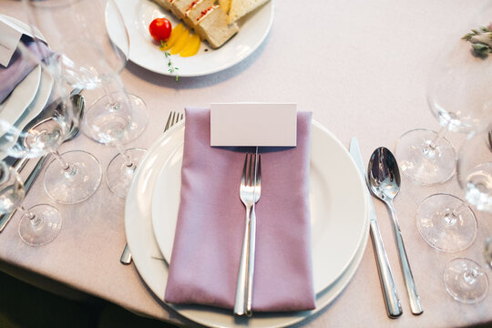 Top view of elegant white empty plate with silver cutlery, violet serviette, transperent vine glass. Luxury restaurant  catering, preparing for meal, evening date. Concept of kitchen design elements.