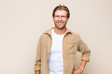 blonde adult caucasic man smiling happily with a hand on hip and confident, positive, proud and...