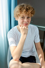 portrait of curly redhead freckled boy looking at camera, young teenager smiles