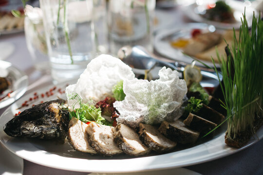 Front view of delicious cooked fish with fresh salad, side dish and microgreen on white plate on table. Tasty dish on celebration banquet. Concept of cooking fine food at home.